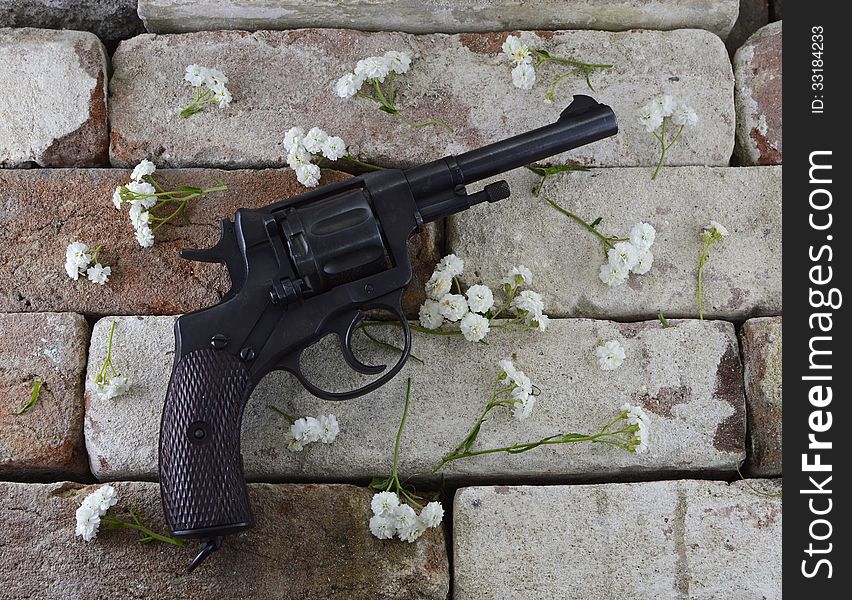 Retro gun with white flowers on brick wall background. Retro gun with white flowers on brick wall background