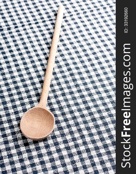 Wooden spoon on a checkered tablecloth, close up