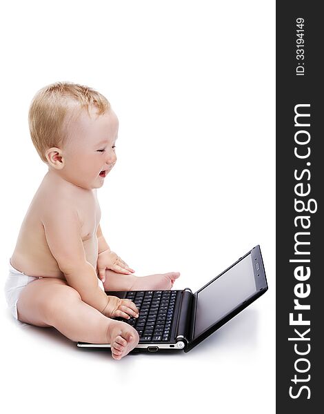 Smiling baby typing on a laptop, positioned sideways, isolated on a white background. Smiling baby typing on a laptop, positioned sideways, isolated on a white background