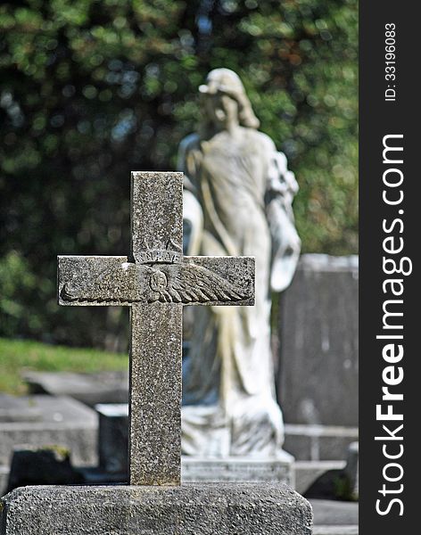 Old cross gravestone of air force pilot with blurred angel in the background. Old cross gravestone of air force pilot with blurred angel in the background