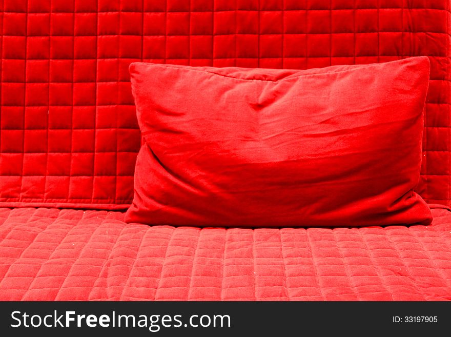Red pillow on red textured blanket