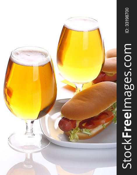 Hot dog with a glass of lager beer on a white background. Hot dog with a glass of lager beer on a white background