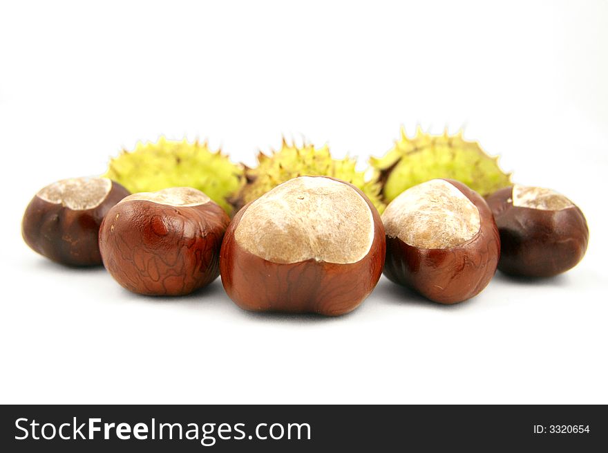 Chestnuts with shells behind. Isolated on white.