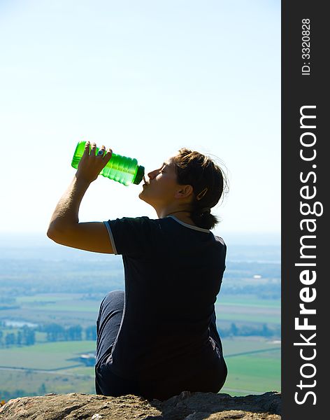 Drinking woman on top of a mountain