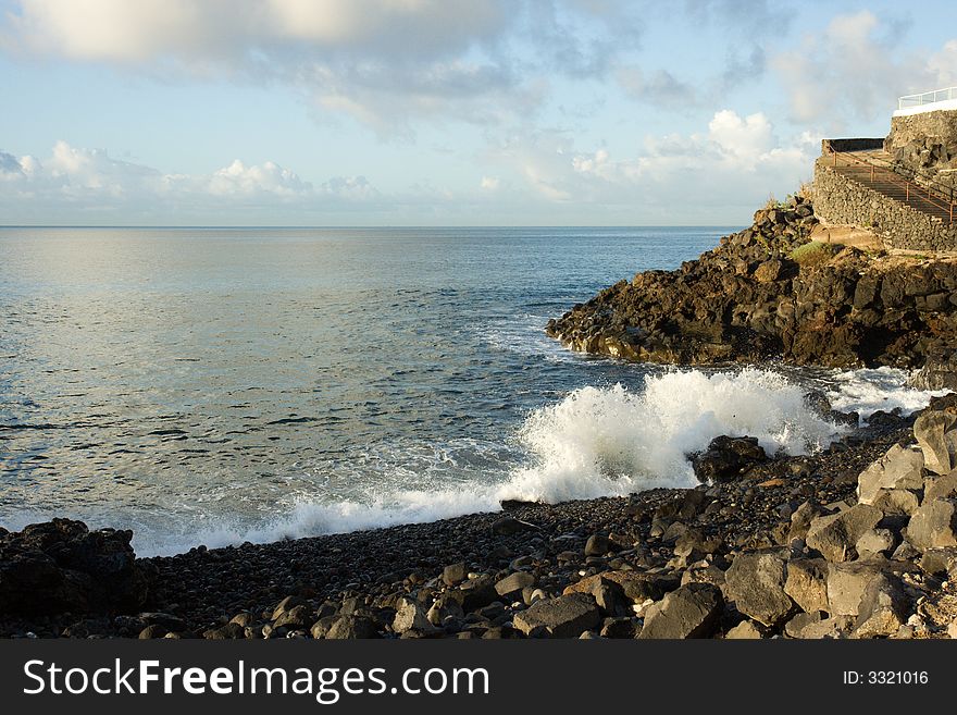 A wave breaks on a rocky shoreline. A wave breaks on a rocky shoreline