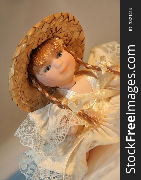 A doll of porcelain with hat and plait / Soft Lights / Cream Scale Colour Background. A doll of porcelain with hat and plait / Soft Lights / Cream Scale Colour Background