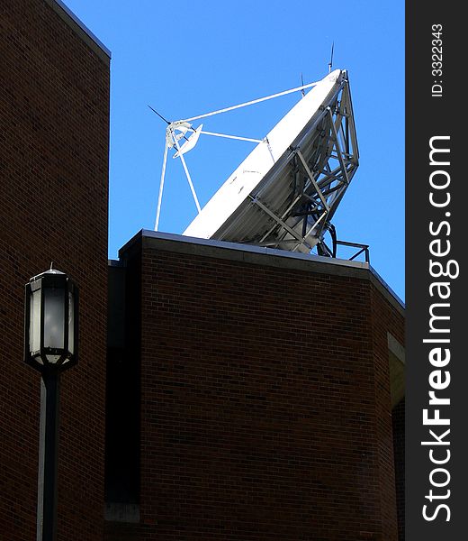 A shot of a large satelite dish on the roof of a building. A shot of a large satelite dish on the roof of a building.