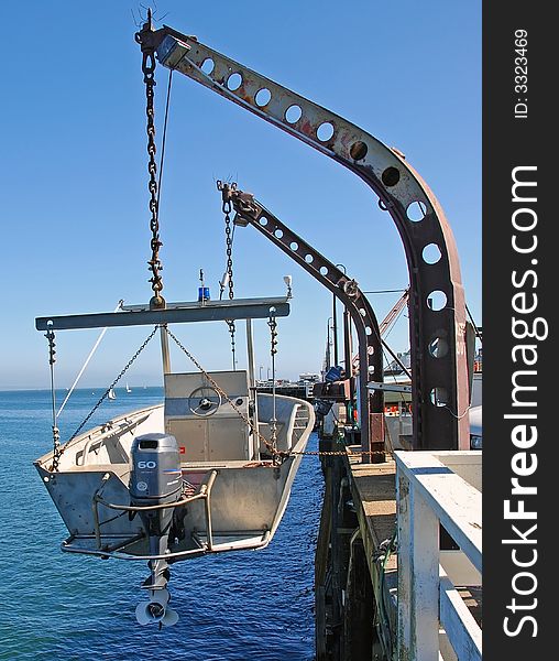 Small fishing troller hanging from davits on a fishing pier. Small fishing troller hanging from davits on a fishing pier