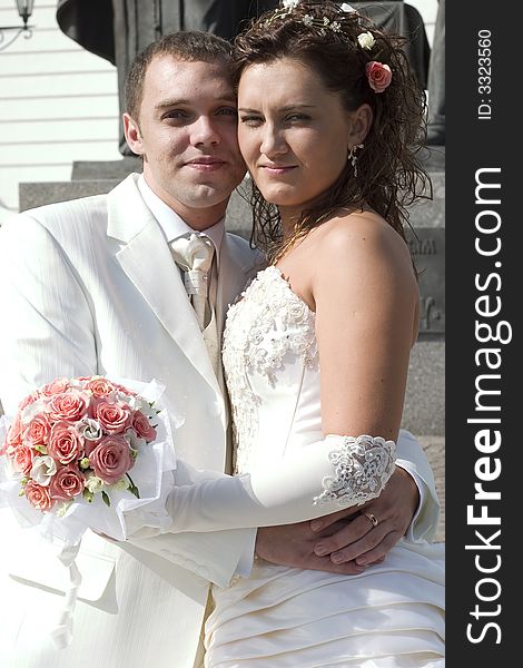 Just married - young couple in wedding wear with bouquet of roses