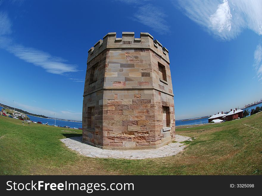 A brick tower in a blue sky & white cloud background in fisheye / ultra-wide angle view, distorted, distortion at La perouse, sydney, nsw, australia. A brick tower in a blue sky & white cloud background in fisheye / ultra-wide angle view, distorted, distortion at La perouse, sydney, nsw, australia