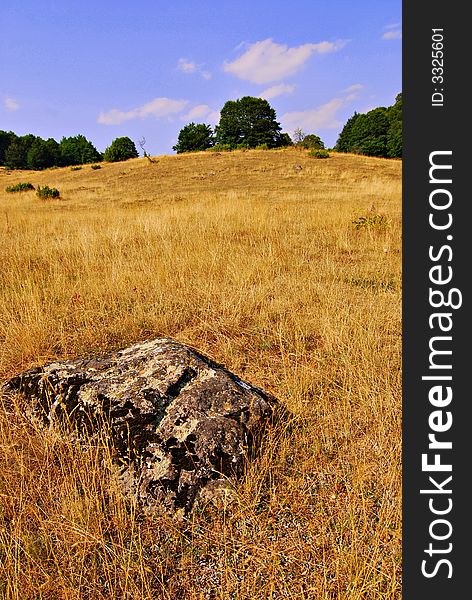 Field and hill landscape view with yellow and blue as dominating colors. Field and hill landscape view with yellow and blue as dominating colors