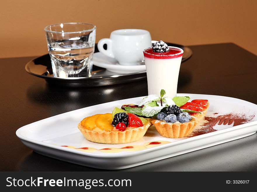 Mixed desert plate with panacotta and summer berries accompanied by coffee tray