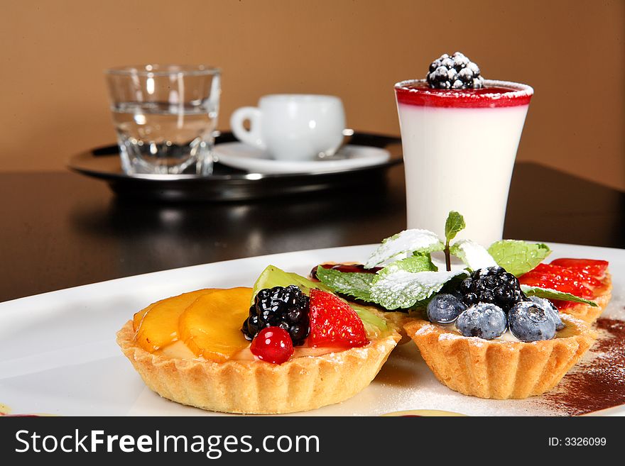 Mixed desert plate with panacotta and summer berries accompanied by coffee tray