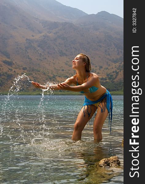 Beautiful blond girl playing with water in a lake