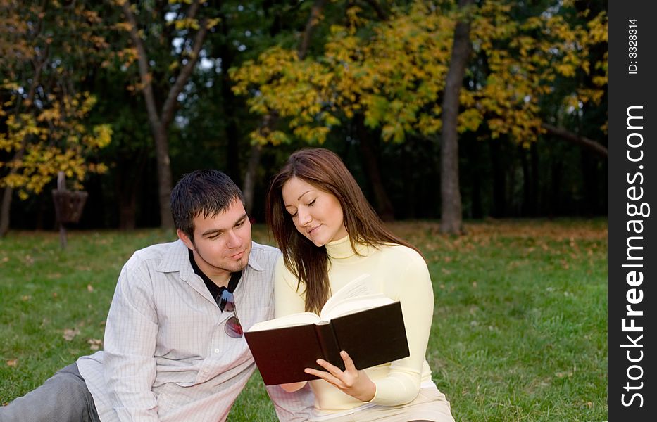 Young couple reading a book at the park. Young couple reading a book at the park