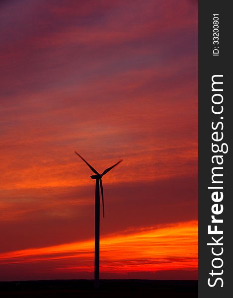 The photograph shows wind turbines on the background of the evening sky. The photograph shows wind turbines on the background of the evening sky.