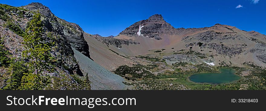 This image of the rugged mountains with some remaining snow fields and the mountain lake was taken in Glacier National Park, Montana. This image of the rugged mountains with some remaining snow fields and the mountain lake was taken in Glacier National Park, Montana.