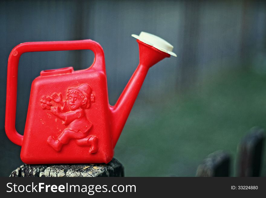 Watering can on the fence of the playground. Watering can on the fence of the playground