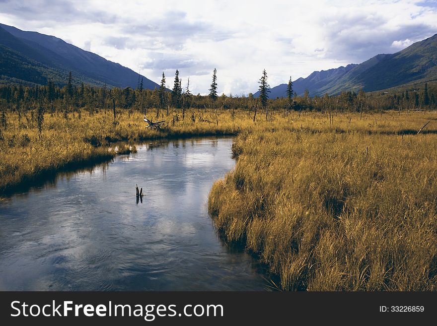 A small river runs through a valley in Eagle River Alaska during the beginning of fall. A small river runs through a valley in Eagle River Alaska during the beginning of fall.
