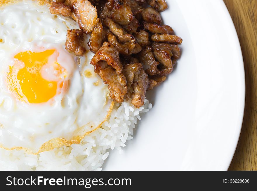 Fried pork with pepper and garlic serve with fried egg and cooked rice on white plate