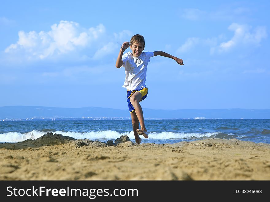 Young boy running along beach by sea