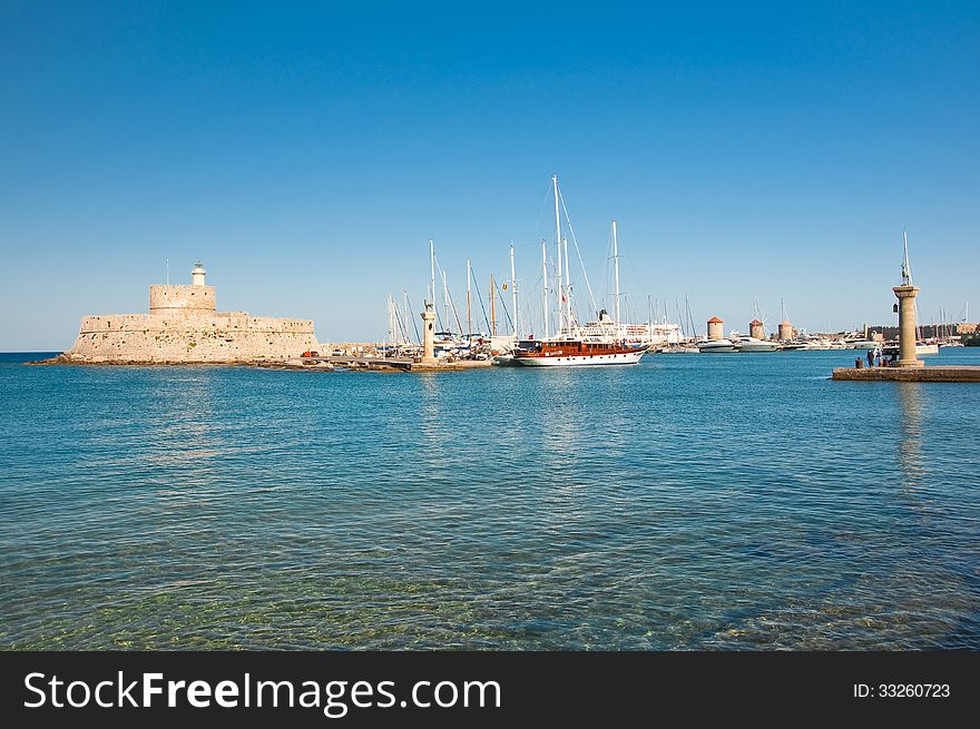 Mandraki harbor and the old lighthouse on July 1, 2013 on an Rodes island, Greece. Mandraki harbor and the old lighthouse on July 1, 2013 on an Rodes island, Greece.