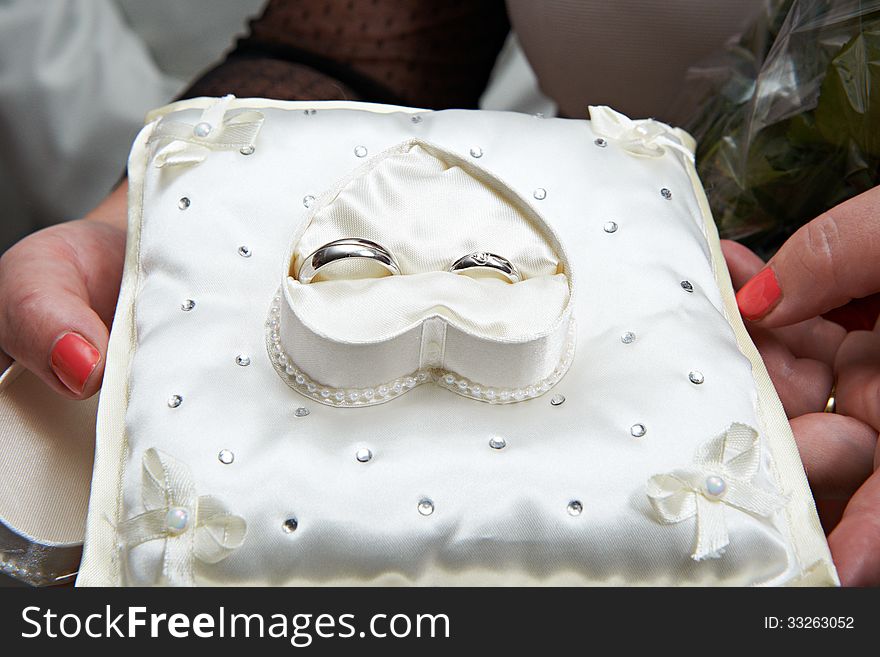 Gold wedding rings on white pillow