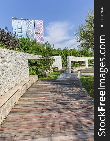 Cultural stone wall with wooden walkway in a city garden. Cultural stone wall with wooden walkway in a city garden