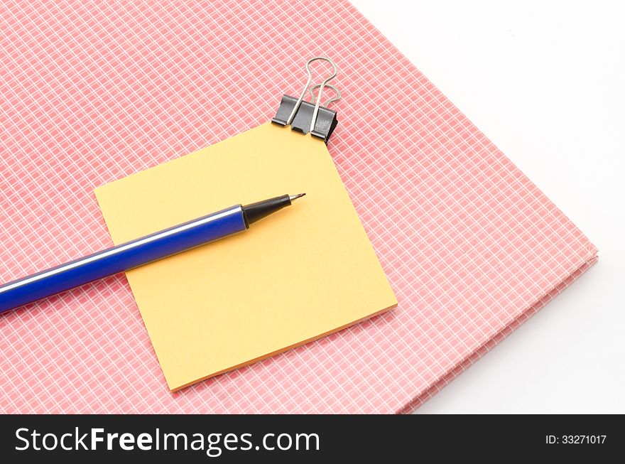 Red notebook with post it and bulldog clip blue pen isolated on white background