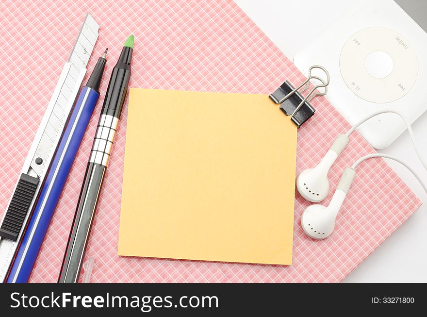 Red notebook with post it and bulldog clip blue pen cutter ear phone isolated on white background