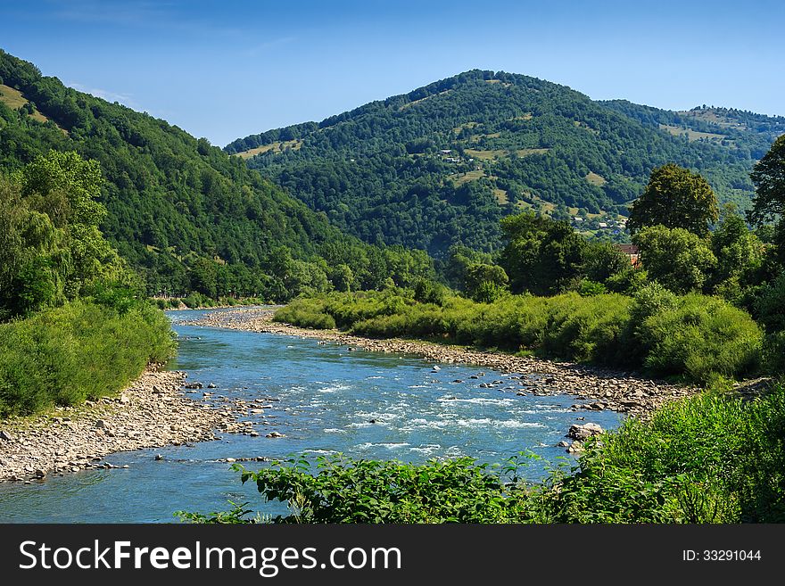 River meanders through the village at the foot of the mountains. River meanders through the village at the foot of the mountains