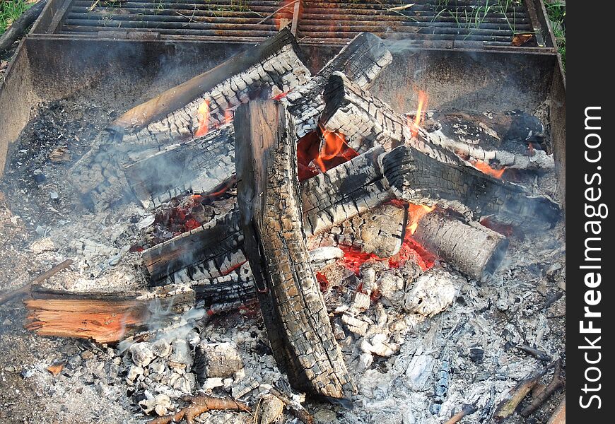 Teepee shape campfire with charred wood, flames and ash in fire pit. Teepee shape campfire with charred wood, flames and ash in fire pit