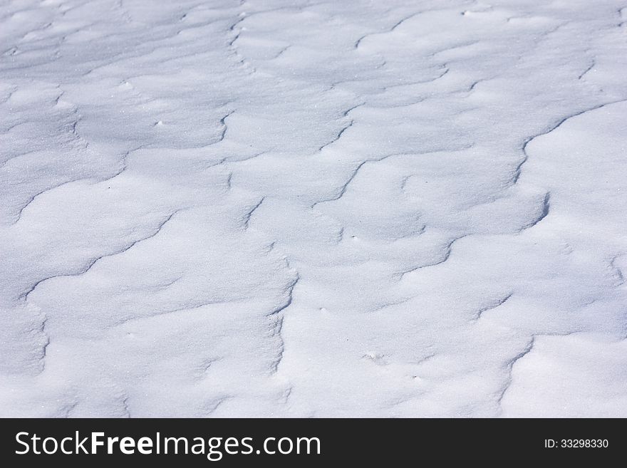 Wavy blue snow surface under bright sunlight, closeup view