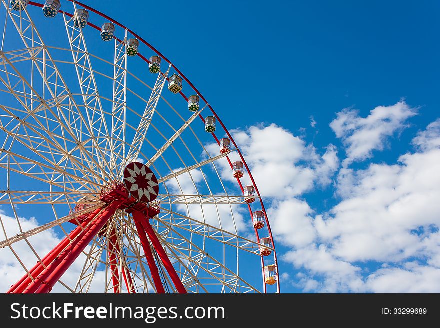Ferris wheel in the summer in the blue cloudy sky. Ferris wheel in the summer in the blue cloudy sky