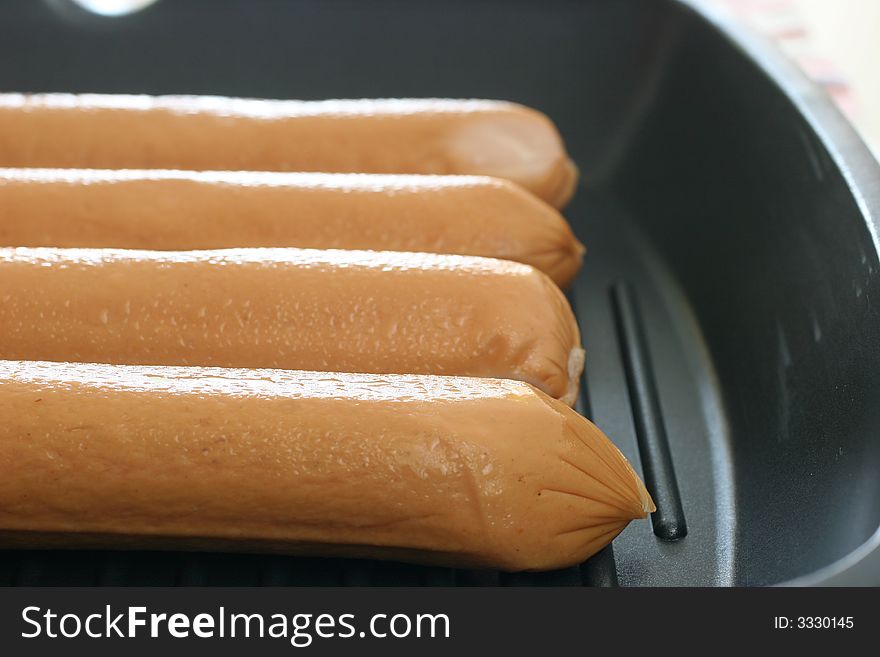 Four frozen but thawing jumbo frankfurters for pan frying