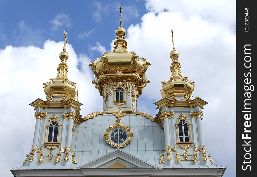 Three gold domes against the background blue sky with clouds.