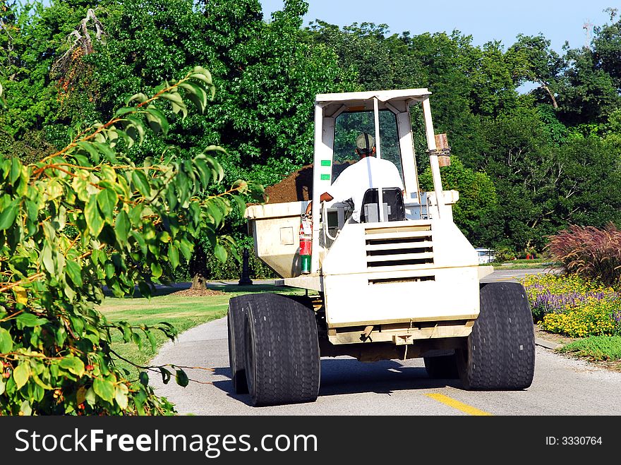 Maintenance man driving front loader in cemetery. Maintenance man driving front loader in cemetery