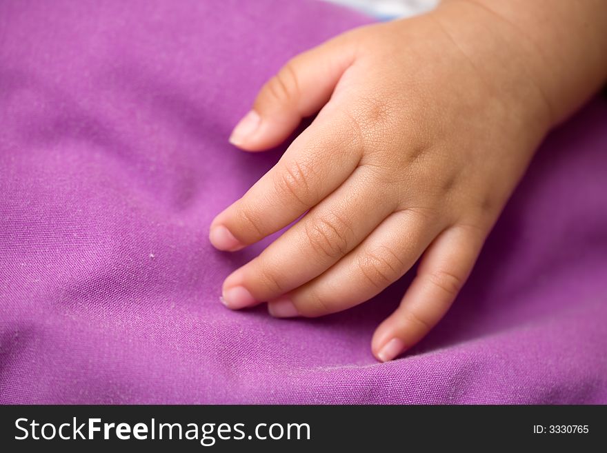 Tiny newborn baby hand close up on a light purple blanket. Tiny newborn baby hand close up on a light purple blanket