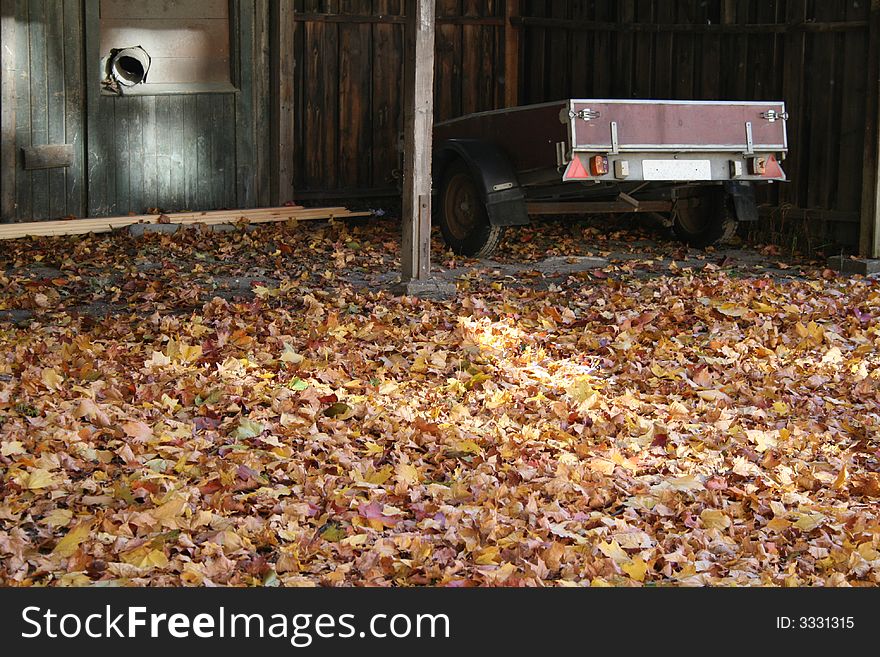 A car trailer parked in a garage surrounded by autumn leaves. A car trailer parked in a garage surrounded by autumn leaves