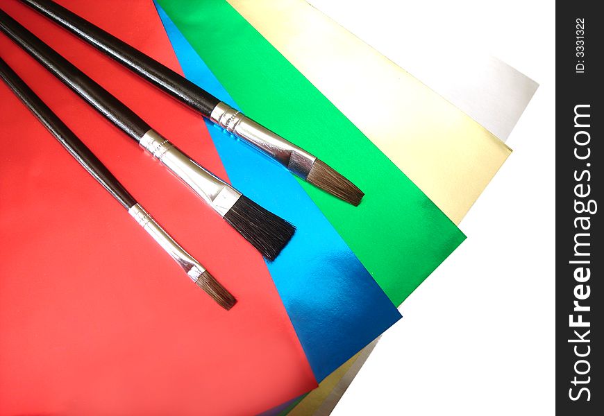Three paint brushes on colored papers