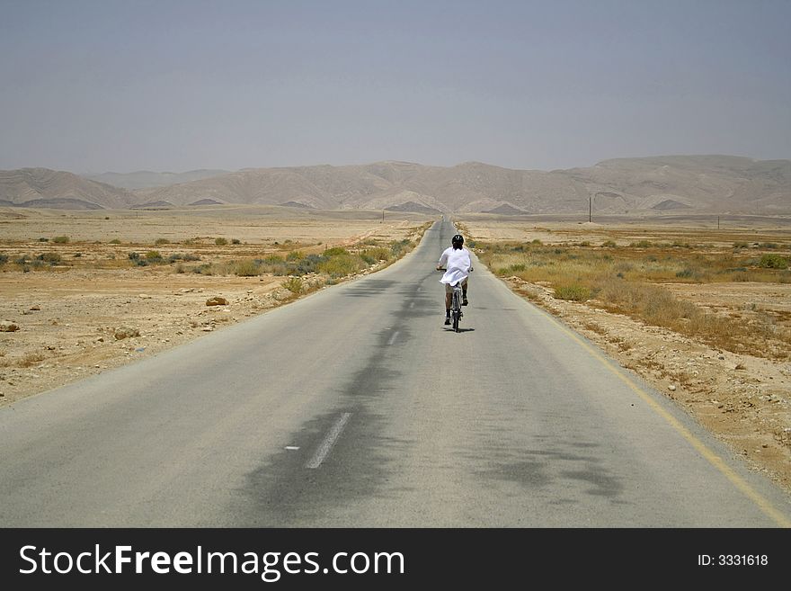 Man Cycling On Desert Road