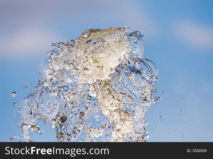 Splash of water on a background of the blue sky with clouds