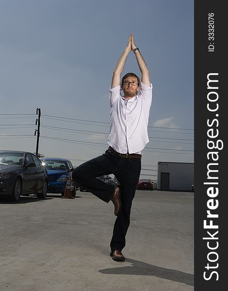 Young working man with beard performs a Yoga stretch on the top a parking lot. Young working man with beard performs a Yoga stretch on the top a parking lot.