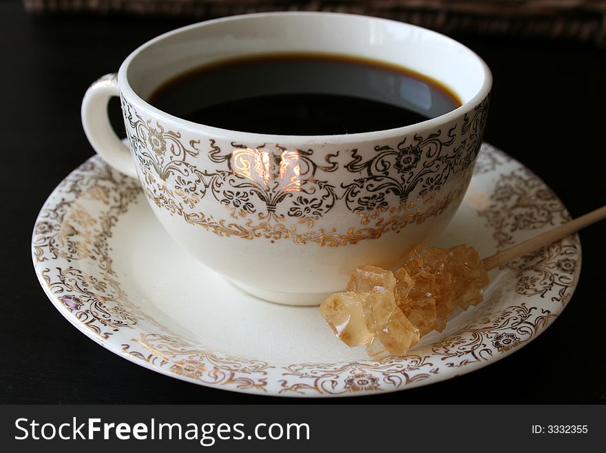 Antique coffee cup with gold patterns and a sugar crystal. Antique coffee cup with gold patterns and a sugar crystal