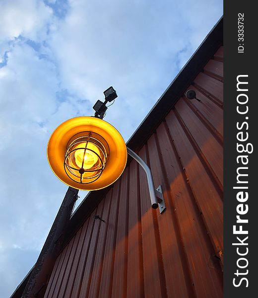 A bright yellow lamp on the side of a building. A bright yellow lamp on the side of a building.