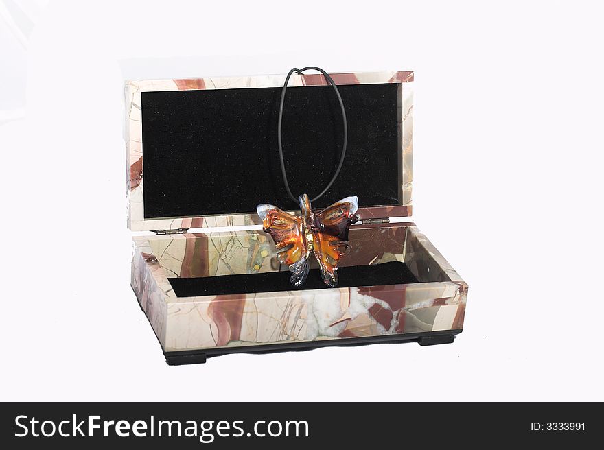 Casket from a color stone with an ornament in the form of the butterfly from multi-coloured glass on a black leather cord on a white background. Casket from a color stone with an ornament in the form of the butterfly from multi-coloured glass on a black leather cord on a white background