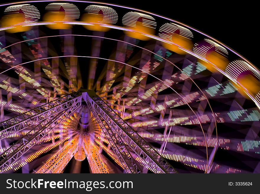 Illuminated ferris wheel at funfair. A night scene. Illuminated ferris wheel at funfair. A night scene.