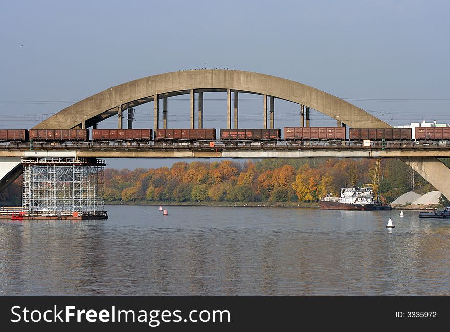 The railway bridge over the river with freight train passing by.