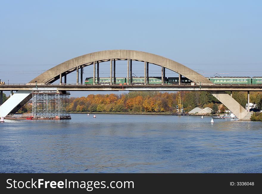 The railway bridge over the river with passenger train passing by.