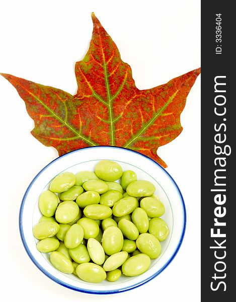 A dish of green beans with red maple leaf on white background